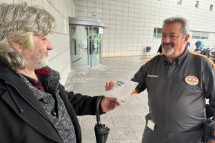 Un membre de l'equip de seguretat entregant un dels díptics informatiu a un pacient